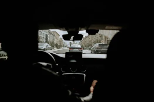 attentive driver monitoring a Korean urban intersection while a generic driver assistance visualization appears on the dashboard, realistic interior photo, safe driving posture, no logo, no text