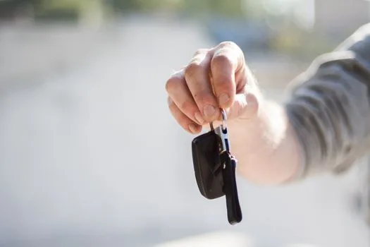 car owner comparing blank vehicle registration document and submission checklist beside generic car key in daylight