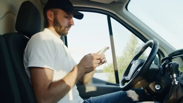 driver checking mobile authentication near parked car