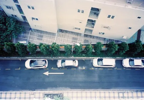 rainy Seoul hospital parking entrance traffic with cars queued beside medical center, realistic editorial photo, no logos