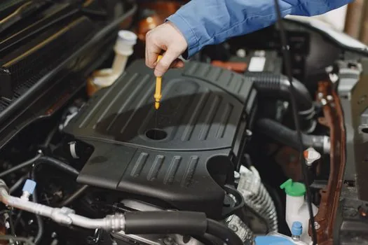 mechanic checking coolant reservoir car engine bay summer