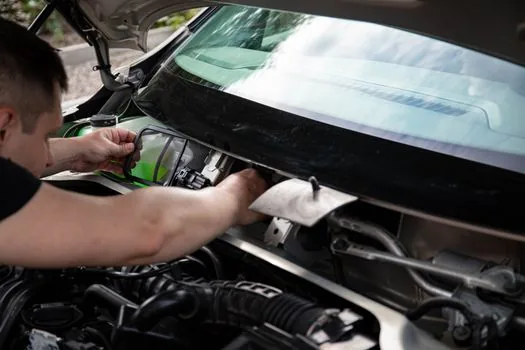close-up of dirty car cabin air filter pulled from glove box, Korean garage daylight, realistic maintenance photo | 먼지 낀 자동차 에어컨 필터를 글러브박스에서 꺼내 확인하는 장면