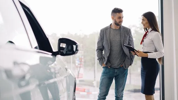 Renault Korea showroom consultant explaining warranty document beside Filante and Grand Koleos brochure, realistic bright dealership photo, no logos enlarged, no readable private data