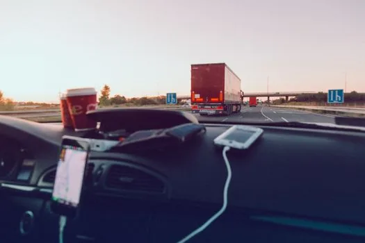 smartphone navigation showing highway rest areas and fuel stop plan, car key and travel bag on desk, realistic Korean holiday travel photo | 휴게소와 주유 지점을 출발 전에 비교하는 장면