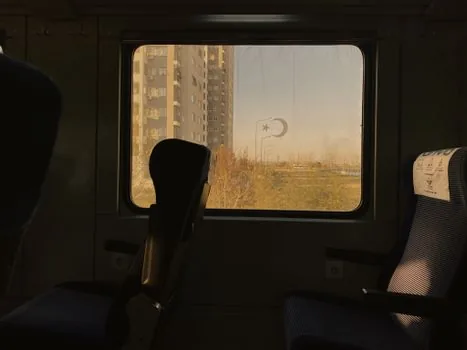 high speed train passenger holding phone ticket beside an empty adjacent seat, realistic Korean travel editorial photo | 승객이 모바일 승차권을 확인하며 옆좌석을 비워둔 열차 내부 장면